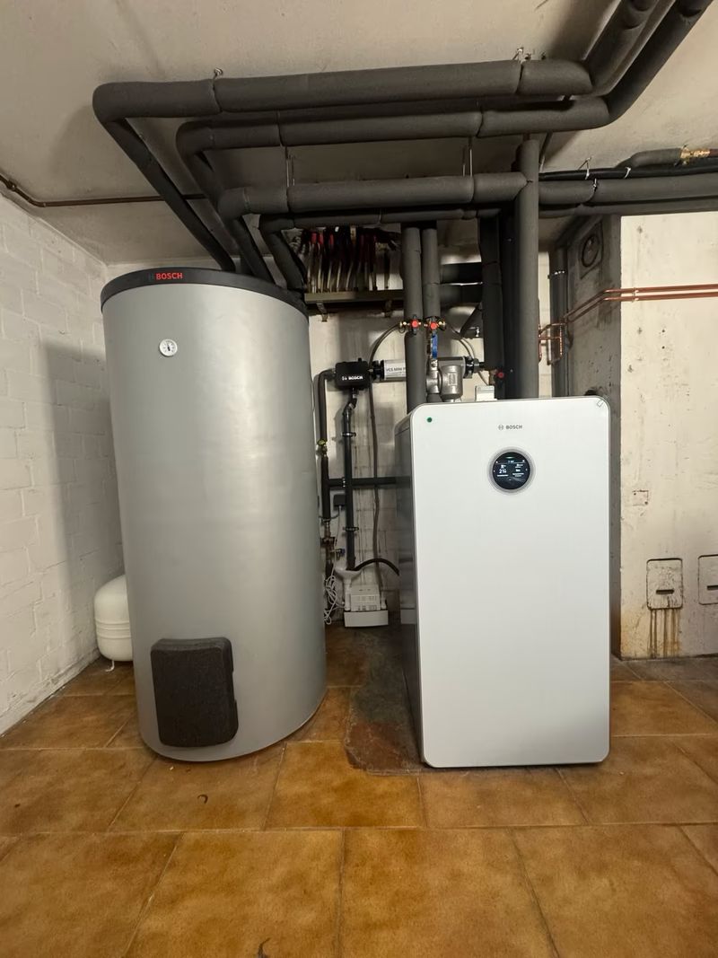 Inneneinheit einer Wärmepumpe neben einem Warmwasserspeicher
