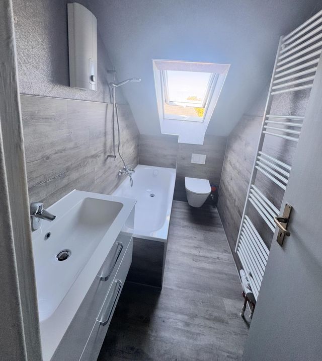 Helles neues Badezimmer mit Waschtisch, WC und Dachfenster